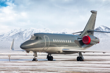 Luxury executive airplane on the winter airport apron on the background of high scenic mountains