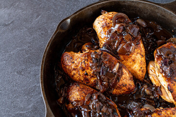 Roasted chicken breast with red onion sauce in a cast iron pan