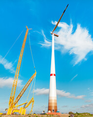 Construction work. Large wind power station nacelle on tower high up. Rotor with one blade. Building and assembling a windturbine. Green energy, ecology, CO2-footprint reduction concept. Wörrstadt  - obrazy, fototapety, plakaty