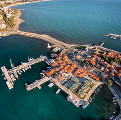 Aerial view of Nessebar, an ancient town on the Bulgarian Black Sea coast with red-roofed houses and piers with yachts and small boats amid turquoise waters