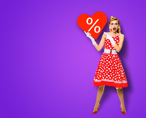 Woman holding red paper heart shape with % sign. Full length body portrait of happy pin up girl...