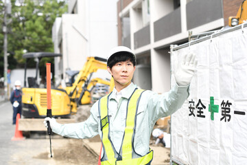工事現場で交通誘導をするガードマンの男性