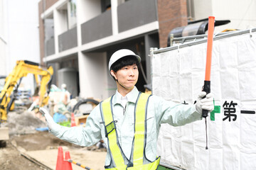工事現場で交通誘導をするガードマンの男性