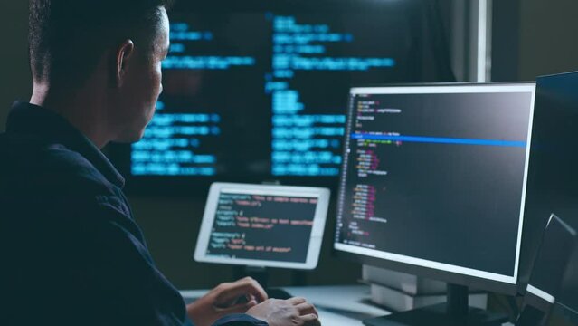 Young Asian man, developer programmer, software engineer, IT support, working hard at night overtime on computer to check coding in bugging system