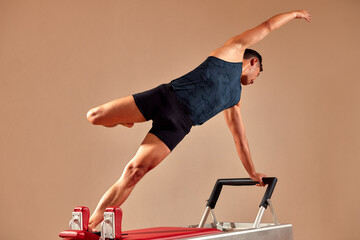 Fit man doing a lunge stretch yoga pilates exercise to strengthen and tone his muscles using a...