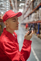 Worker using the two-way radio in the storage area © zinkevych
