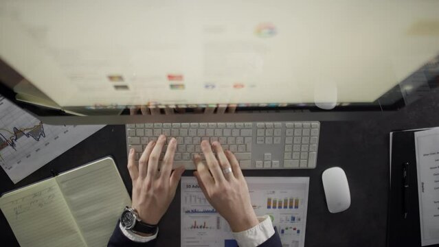Close-up of the workplace of a businessman in the office. Male hands stop documents and type on a keyboard on a table with a computer. High quality 4k footage
