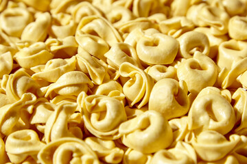 Tortellini pasta with prosciutto food background. Italian stuffed pasta