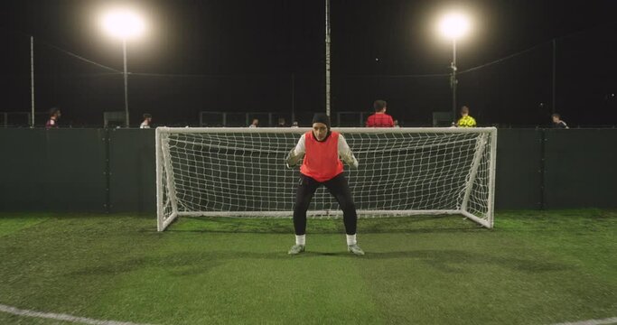 Female goal keeper in hijab in soccer field at night