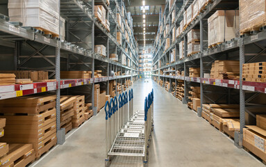 A row of trolleys for customers in a large warehouse in the aisle between shelves and racks