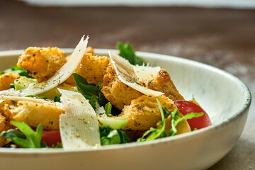 Salad with vegetables, croutons and parmesan in a plate. Close-up, selective focus