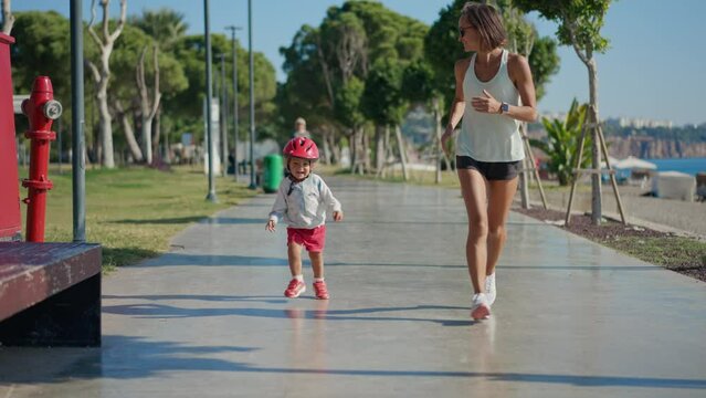 Caucasian woman jogging near the beach with her little son.