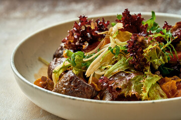 Salad with liver and greens in a plate. Close-up, selective focus.