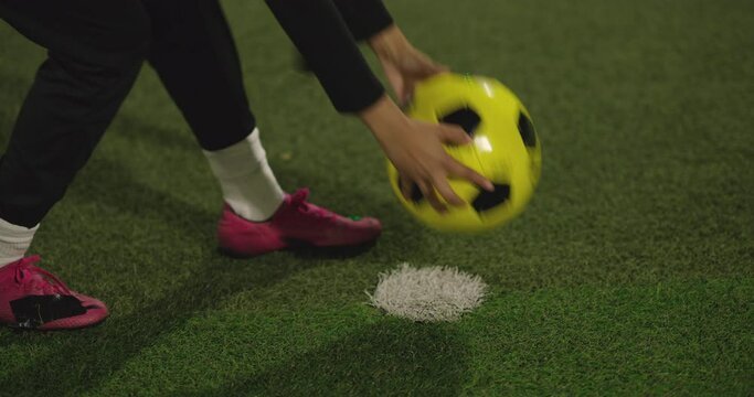 Low section of female soccer player kicking ball in soccer field at night