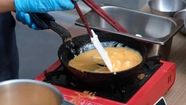 The cook is making an omelet in a pan