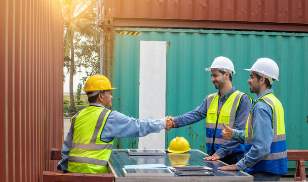 Technicians in safety helmets and uniforms with having handshaking and looking upward, a collaboration concept