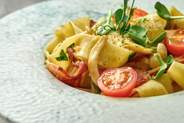 Pasta with bacon and tomatoes in a plate. Close-up, selective focus.