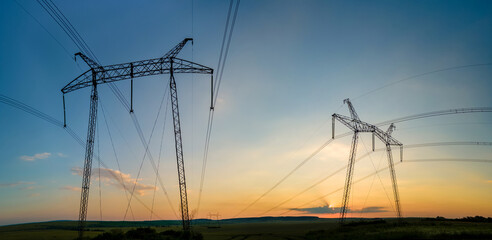 Fototapeta premium High voltage towers with electric power lines at sunset