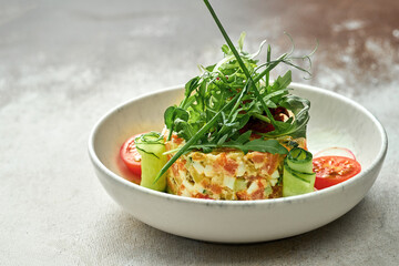 Salad with vegetables and salmon in a plate on a textured background. Close-up, selective focus