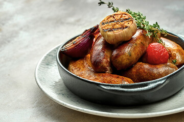 Oven-baked sausages of different types on a plate on a textured background. Close-up, selective focus
