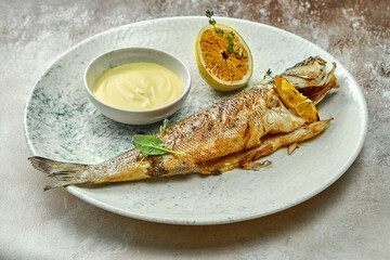 Whole fried seabass with sauce in a plate. Close-up, selective focus