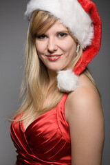 pretty christmas girl with santa claus hat in front of a grey background