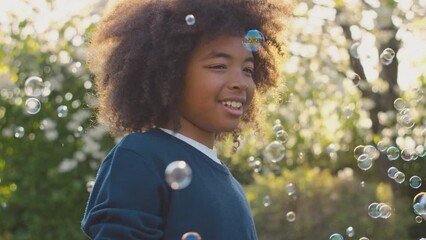 Smiling boy outdoors having fun playing with bubbles in garden -shot in slow motion - Powered by Adobe