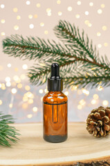 A brown bottle with a pipette against the background of garland lights and Christmas tree branches. Mockup of a brown bottle with a cosmetic product on a Christmas background. Christmas sales and