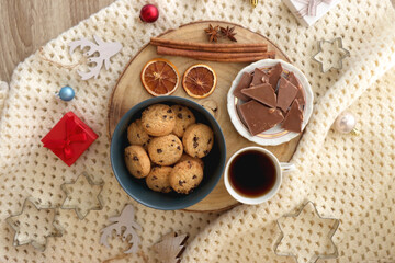 Various Christmas decorations, cup of tea or coffee, sweets, small presents, knitted blanket and candles. Flat lay.