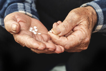 An elderly man holds pills in his hand. Taking pills to treat the disease