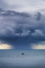 Small sighing boat being chased by huge downpour out to sea. Stormy seas and dark clouds