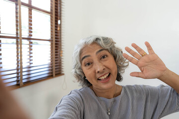 Happy Asian Elderly taking selfie photos with smartphone together in house. Portrait Senior people smiling and looking at camera. - obrazy, fototapety, plakaty