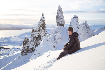 Old Man of Storr in the snow, Isle Of Skye.  Person sat in snow up a mountain