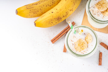 Autumn vegan cinnamon banana smoothie, shake or yogurt in glass jar on the light background. Healthy food 