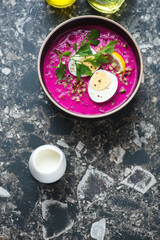Obraz na płótnie Canvas Bowl of cold beetroot soup with kefir on a dark-grey granite background, vertical shot with space, high angle view
