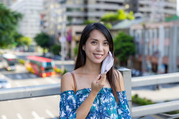 Cheerful woman take off her face mask in city