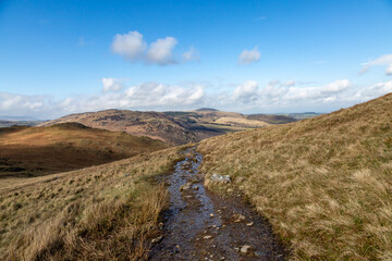 Looking along a pathway in the Lake District, with a blue sky overhead