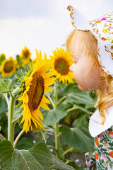 A girl sniffs a sunflower in a field.