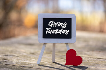 Giving Tuesday text message on chalkboard easel soft bokeh background copy space