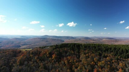 Peak autumn leaf color at Spruce Knob, the highest point in the state of West Virginia on a fall day. The aerial camera shot tracks left over the peak revealing an alpine meadow.