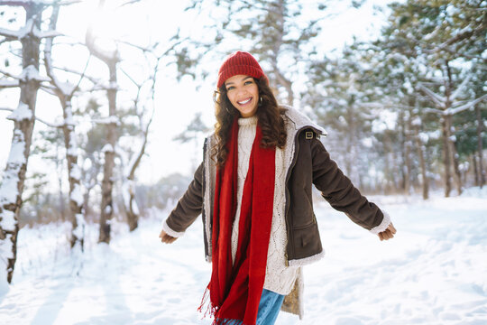 Happy woman standing among snowy trees and enjoying first snow. Holidays, rest, travel concept