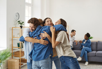 Happy friends who haven't seen each other for long time are hugging during meeting at home. Male...