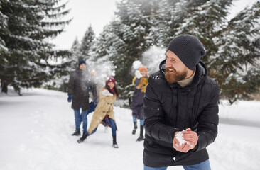 Overjoyed diverse young people play snowballs enjoy active winter weekend in forest. Smiling...