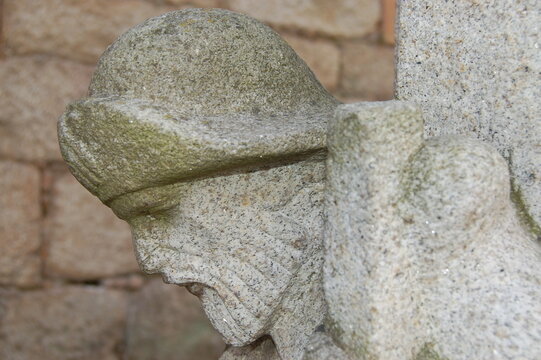 Very old pilgrim figure head sculpted on a column of a building in Tui in Portugal.