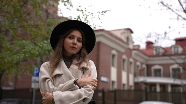 Gorgeous girl in a coat and hat looks at the camera