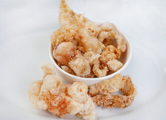 Perfectly crisp, pork rind or crackling in white bowl with copy space