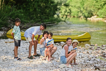 Mother with five kids against canoe in rocky shore of a calm river in Triglav National Park,...