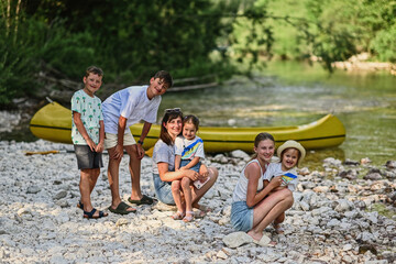 Mother with five kids against canoe in rocky shore of a calm river in Triglav National Park, Slovenia.