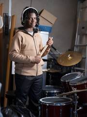 Portrait of teenage boy standing next to drums