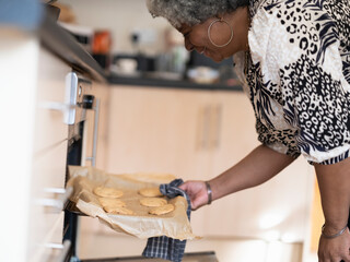 Mother taking cookies out of oven